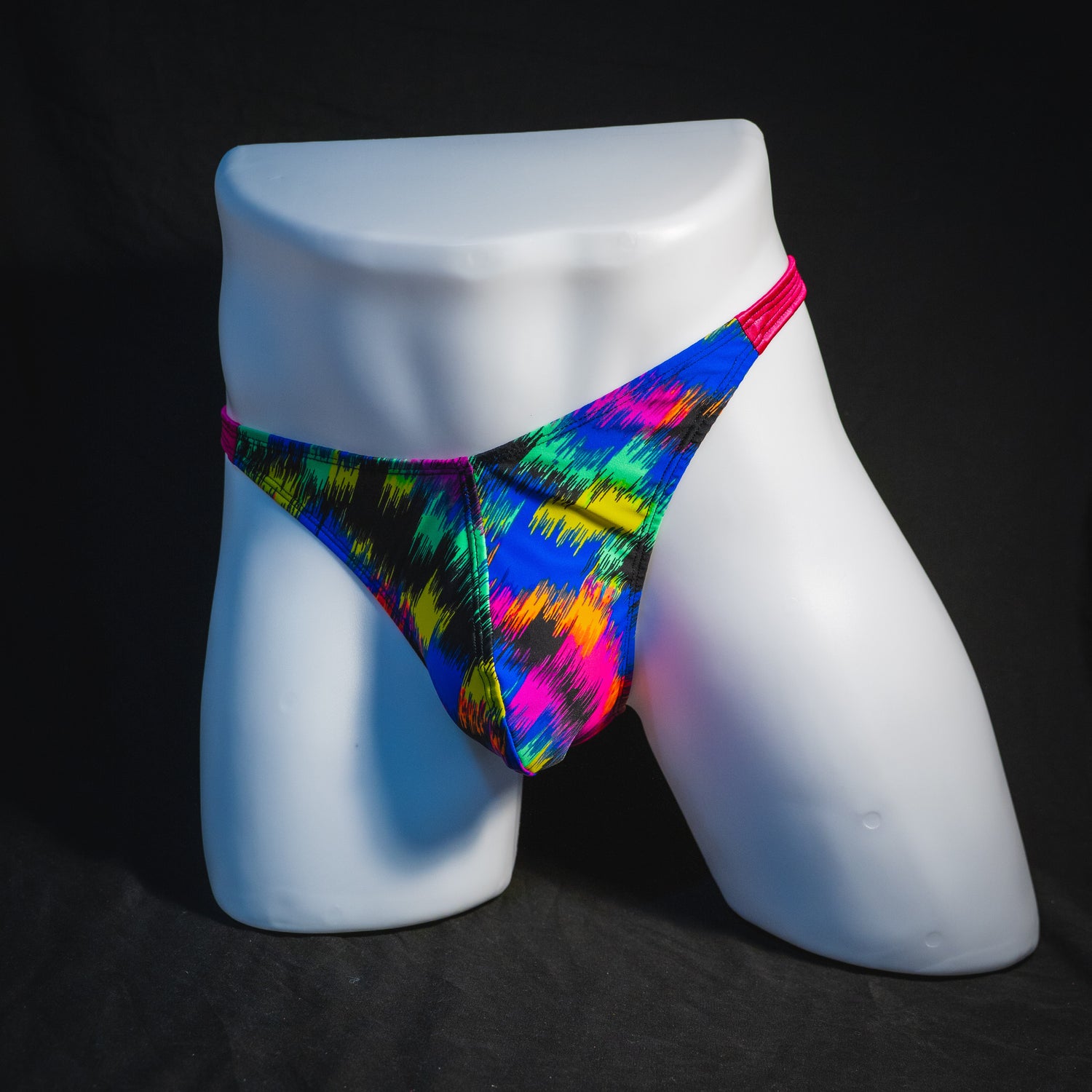 Men's rainbow splash with pink straps thong underwear, classic cut, angled full front view.