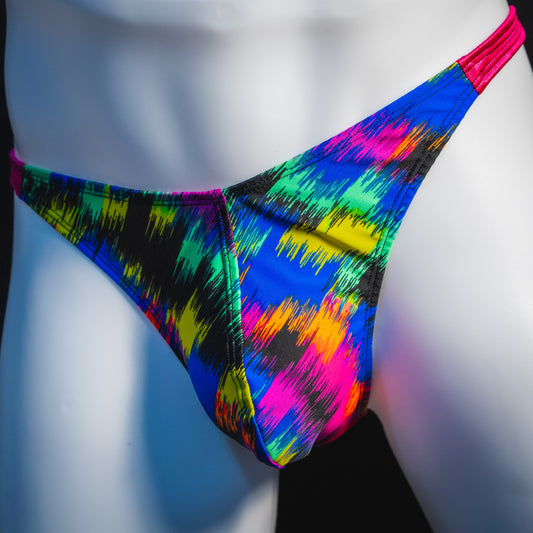 Men's rainbow splash with pink straps thong underwear, classic cut, angled front view.