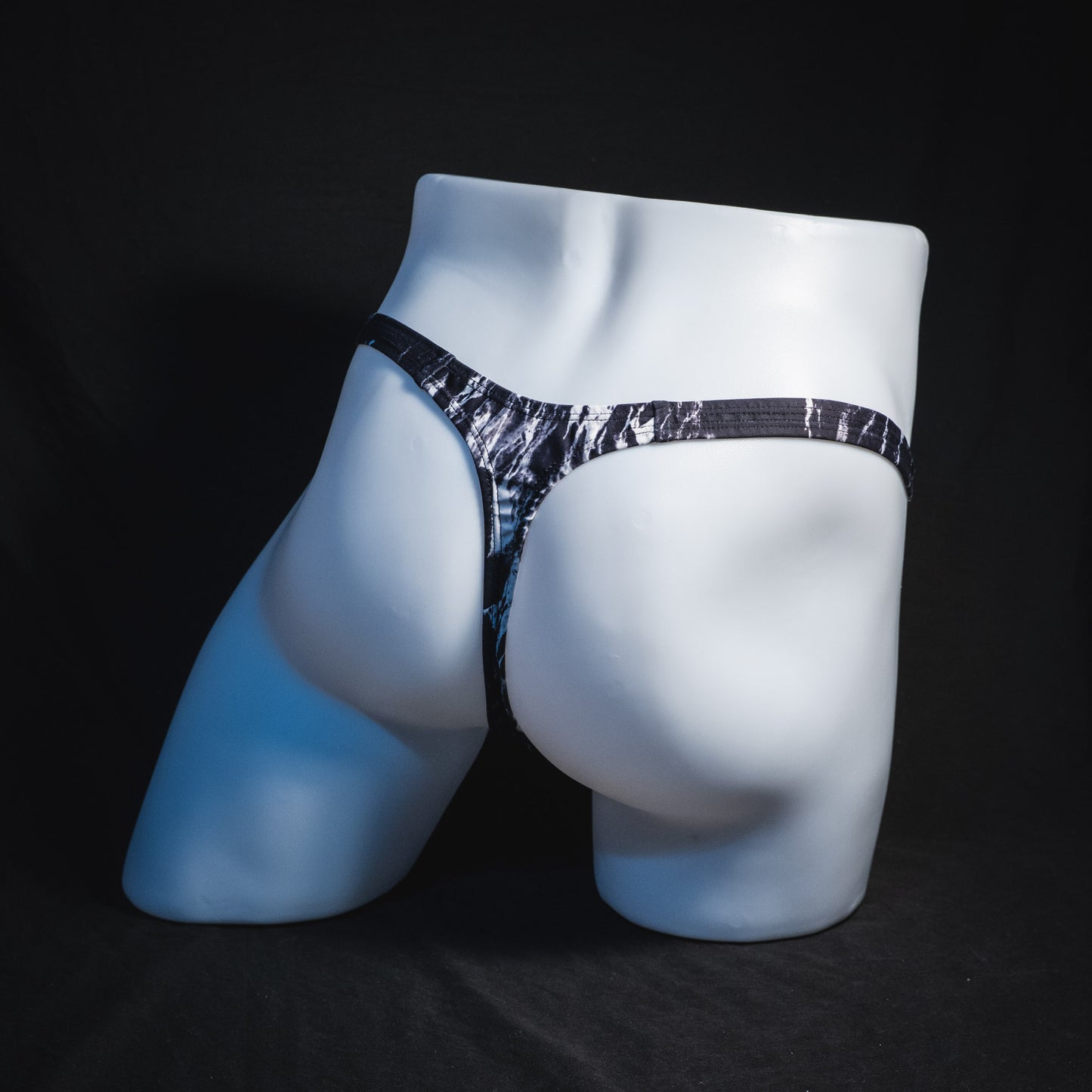 Men's black and white marble thong underwear, tower cut, full angled rear view.
