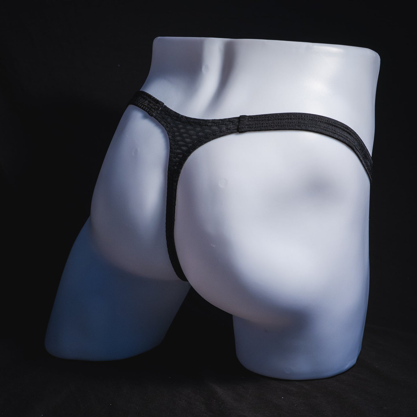 Men's black athletic mesh thong underwear, classic cut, full angled rear view.