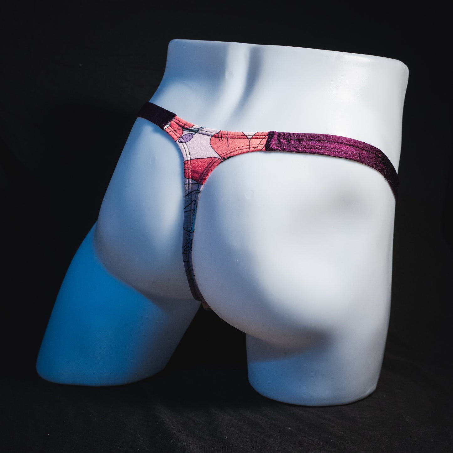 Men's purple floral thong underwear, classic cut, full angled rear view.