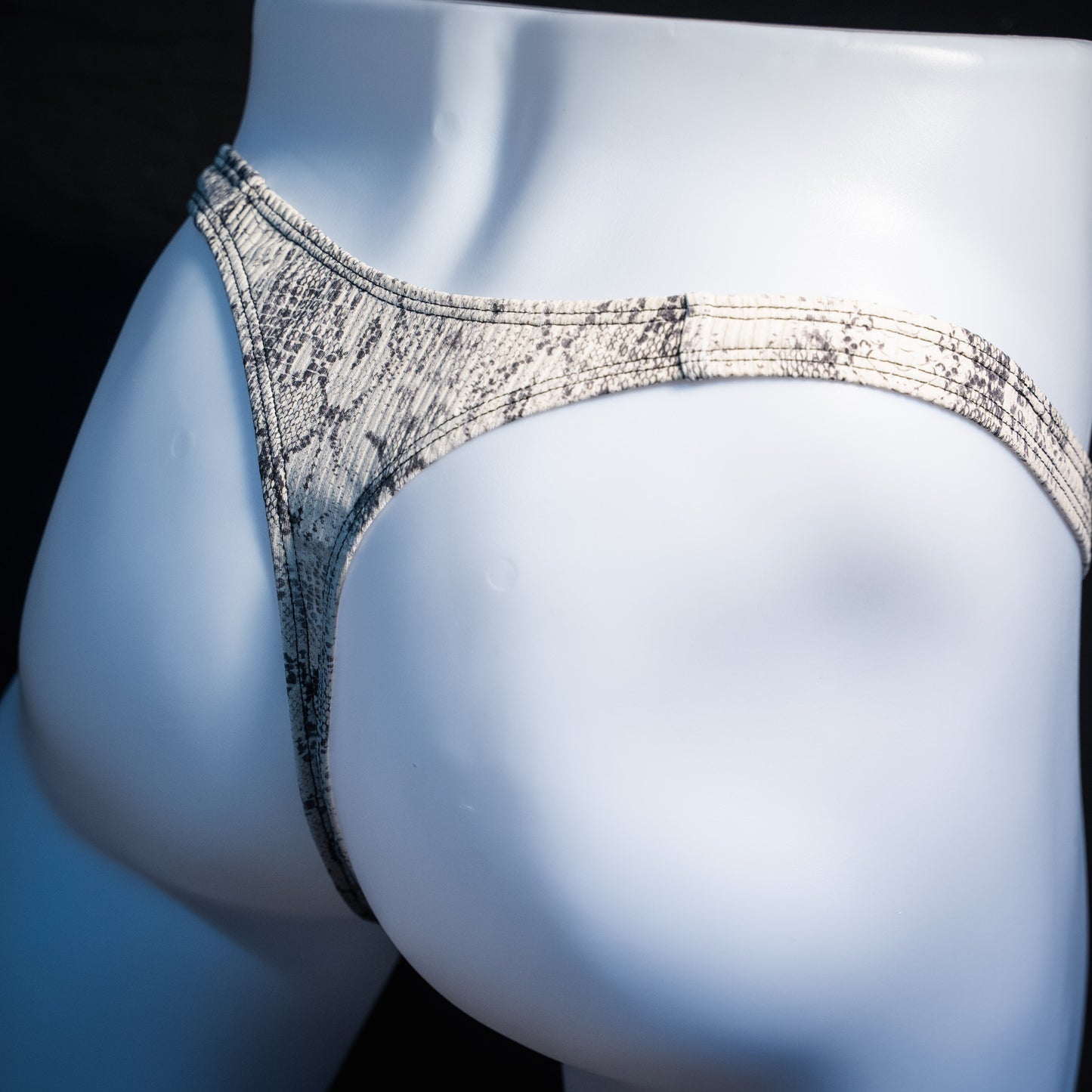 Men's beige snakeskin thong underwear, ribbed fabric, slim cut, rear view.