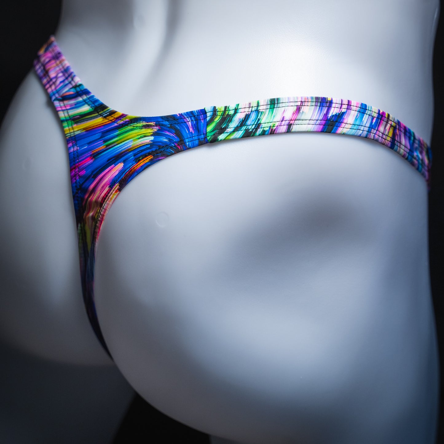 Men's colorful light trails thong, slim cut, angled rear view.