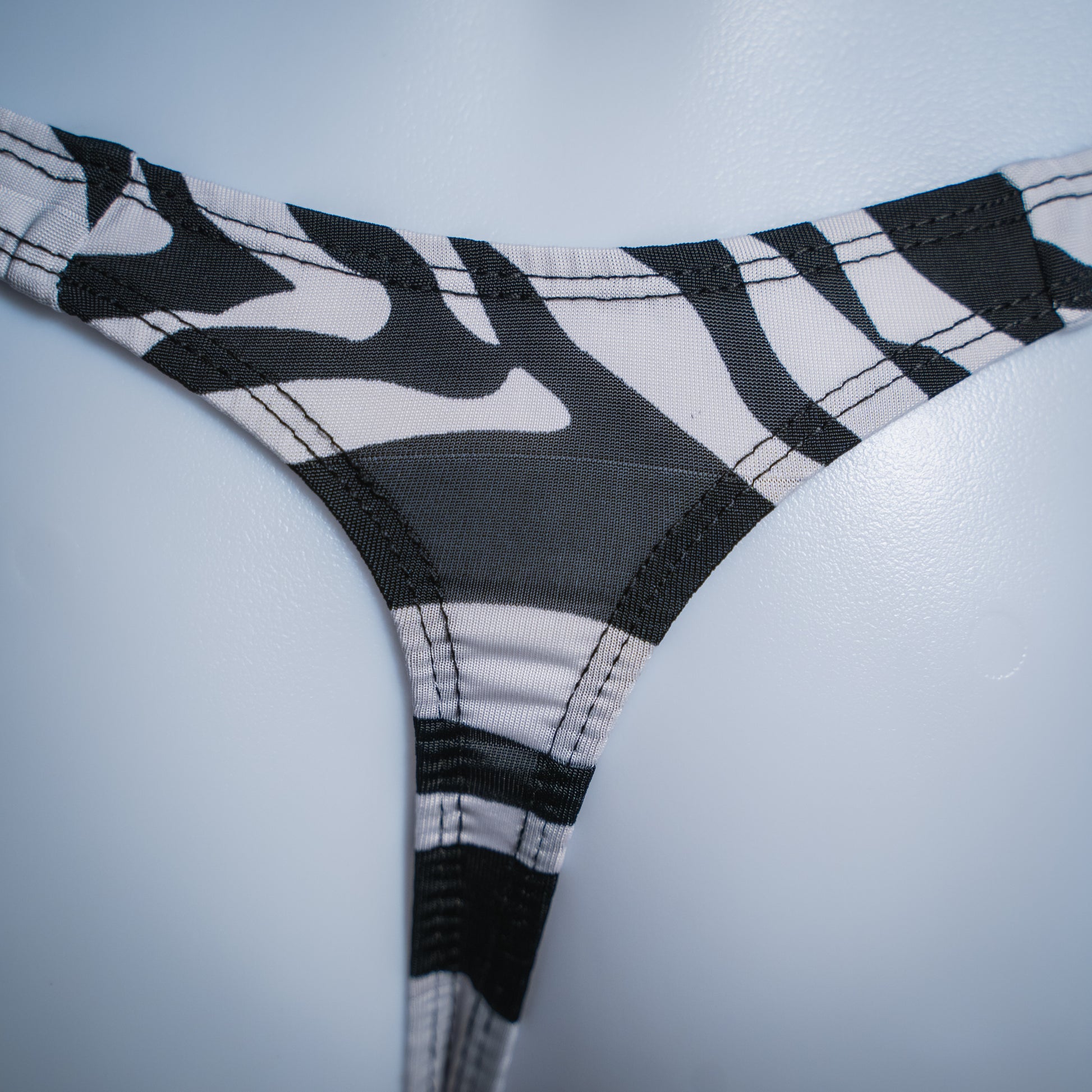 Men's zebra spandex thong, slim cut, closeup rear view.