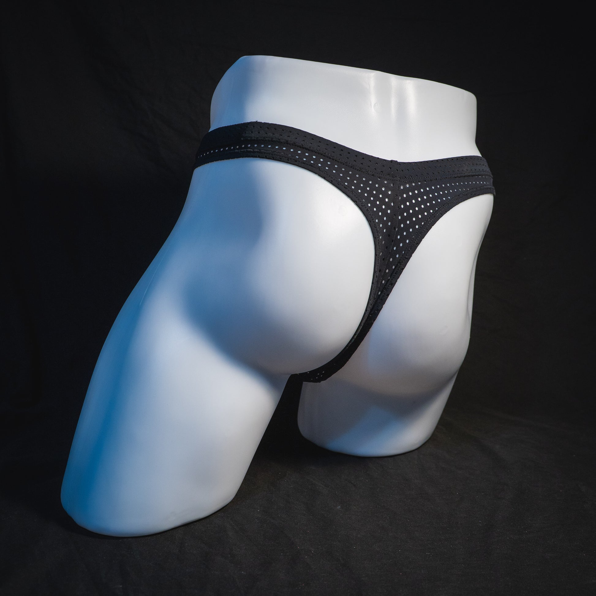 Men's black mesh pre-release thong underwear, angled full rear view.