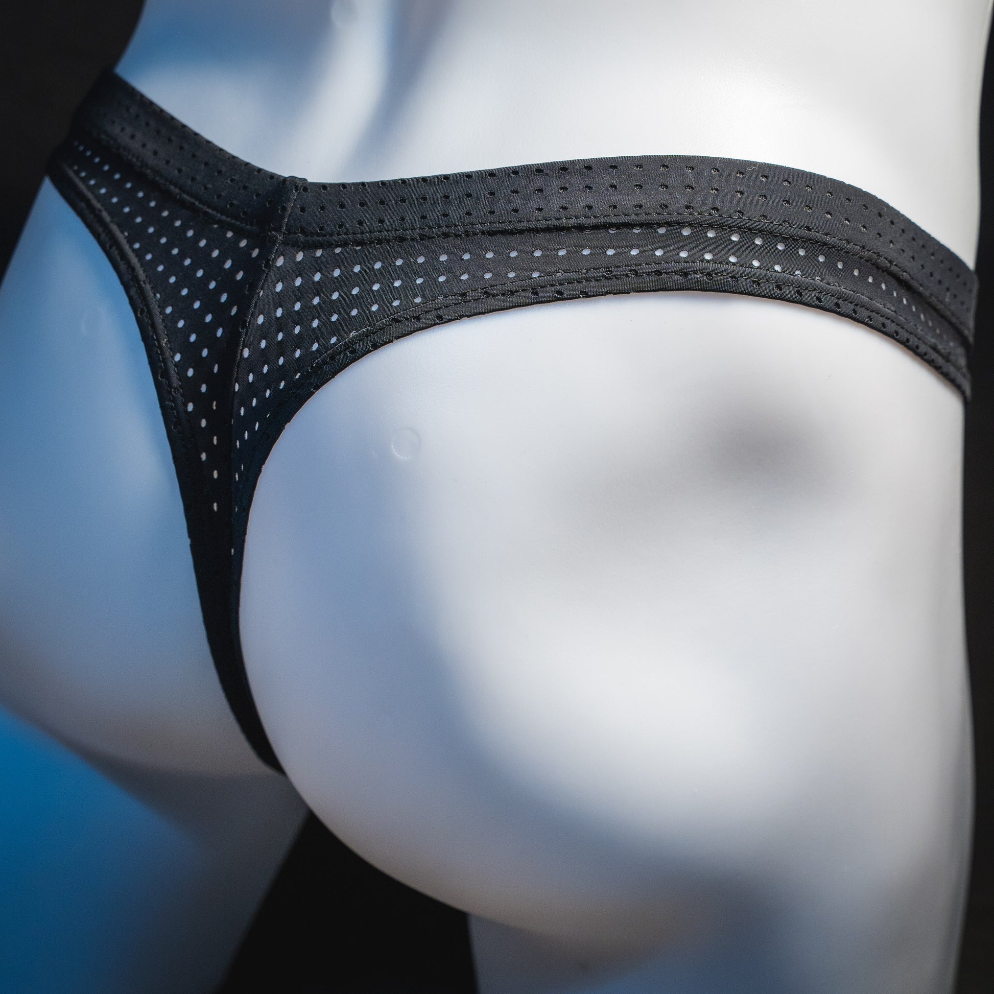 Men's black mesh pre-release thong underwear, angled rear view.