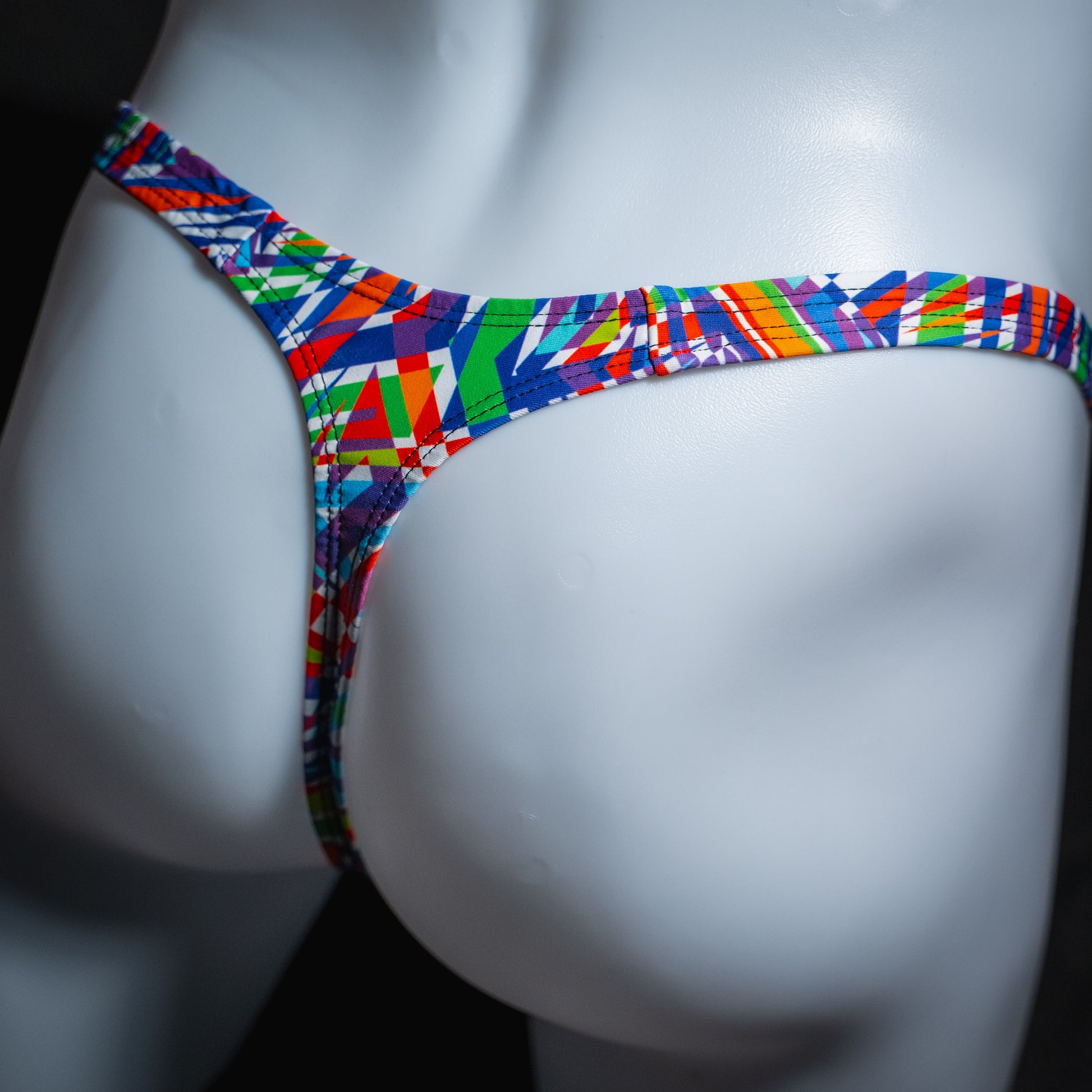 Men's bold colorful thong underwear, classic cut, angled rear view.