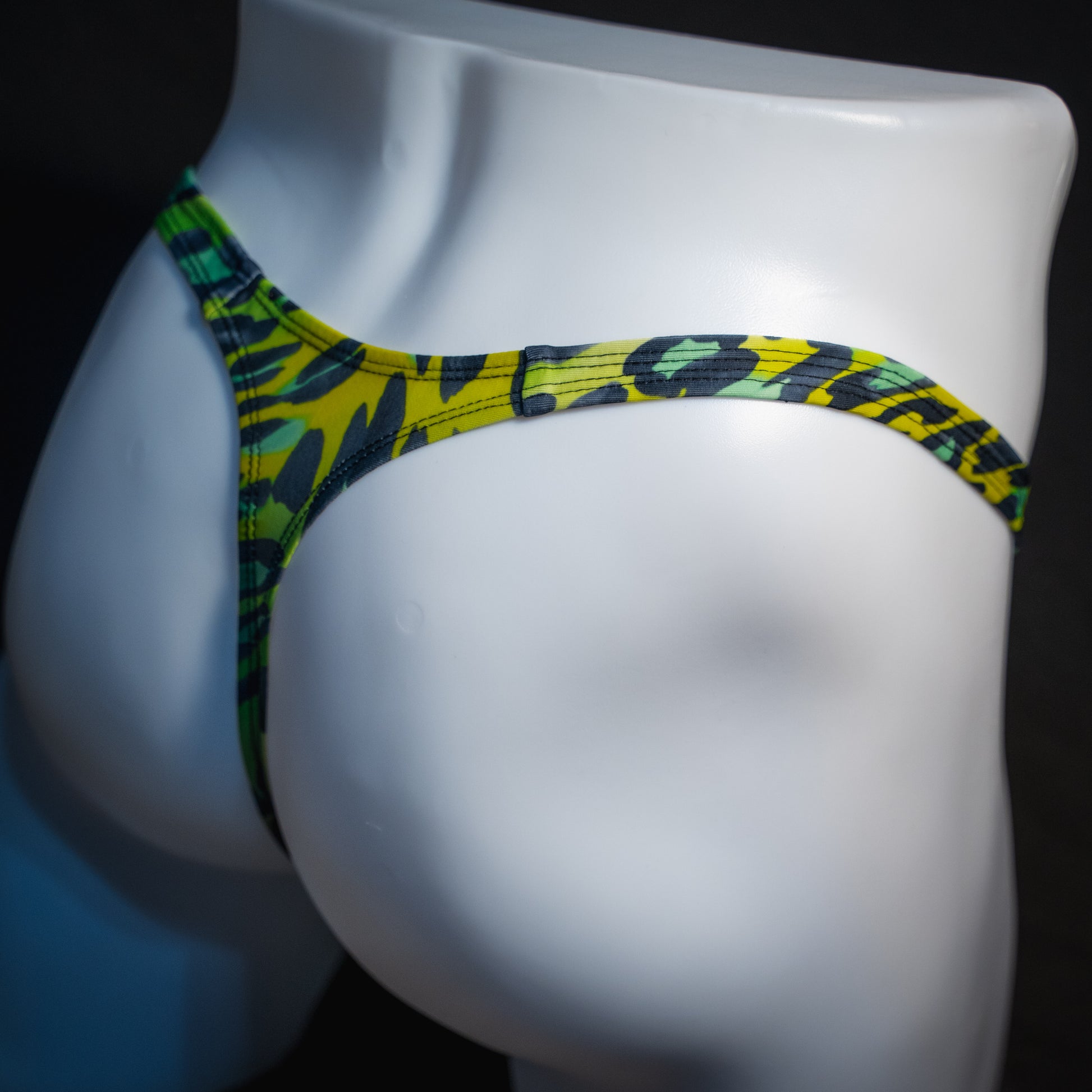 Men's green leopard print thong underwear, slim cut, angled rear view.