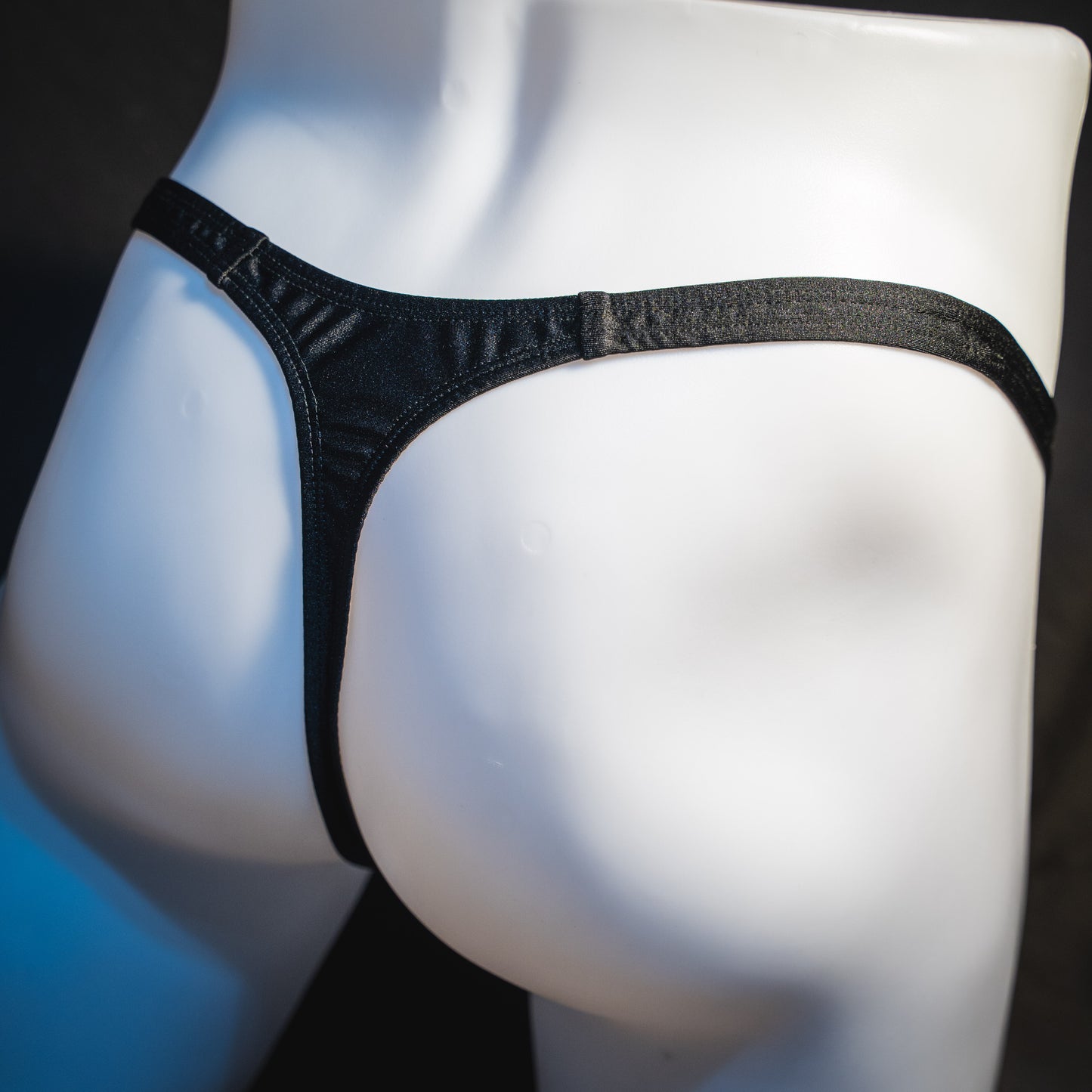 Men's half mesh solid black thong underwear, classic cut, rear angled view.