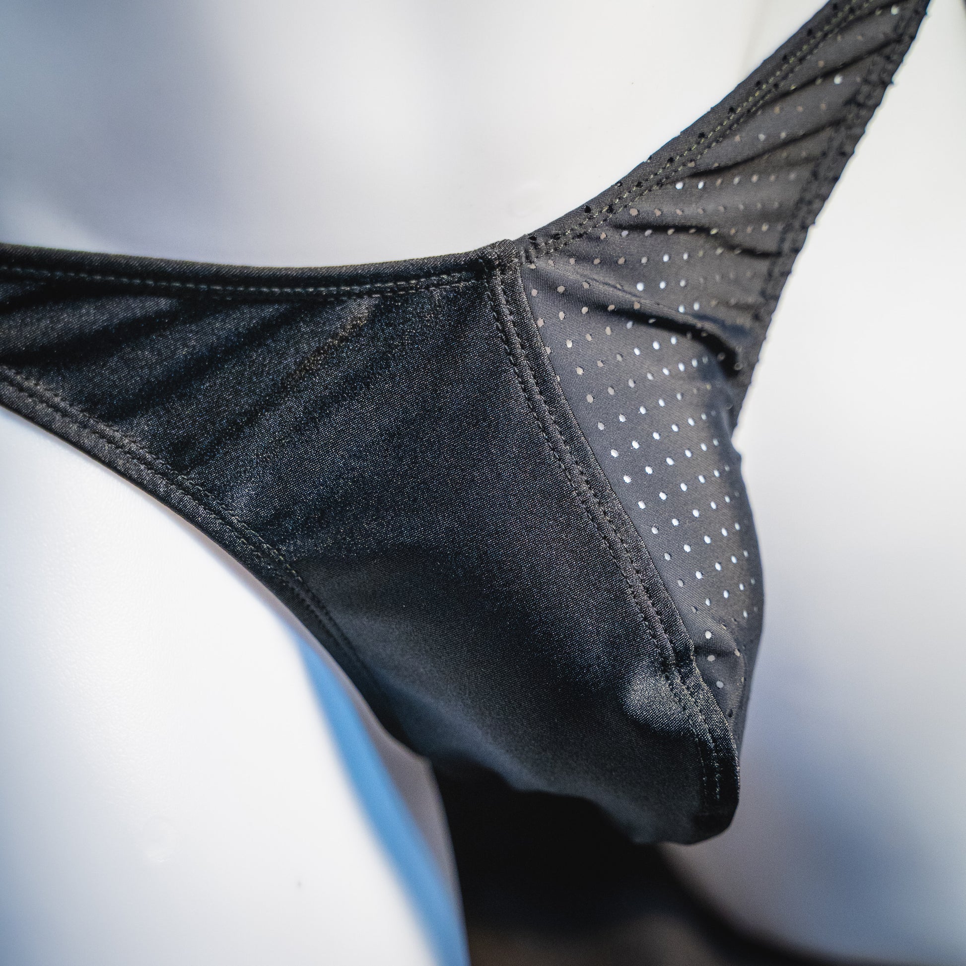 Men's half mesh solid black thong underwear, classic cut, closeup front angled view.