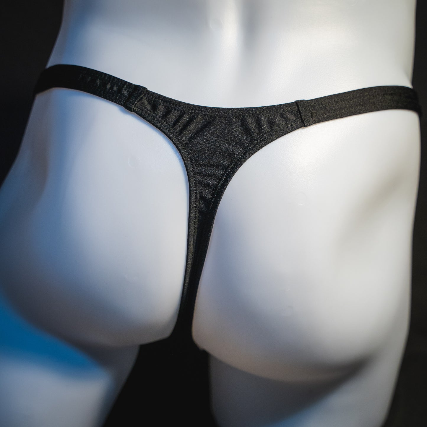 Men's half mesh solid black thong underwear, classic cut, rear view.