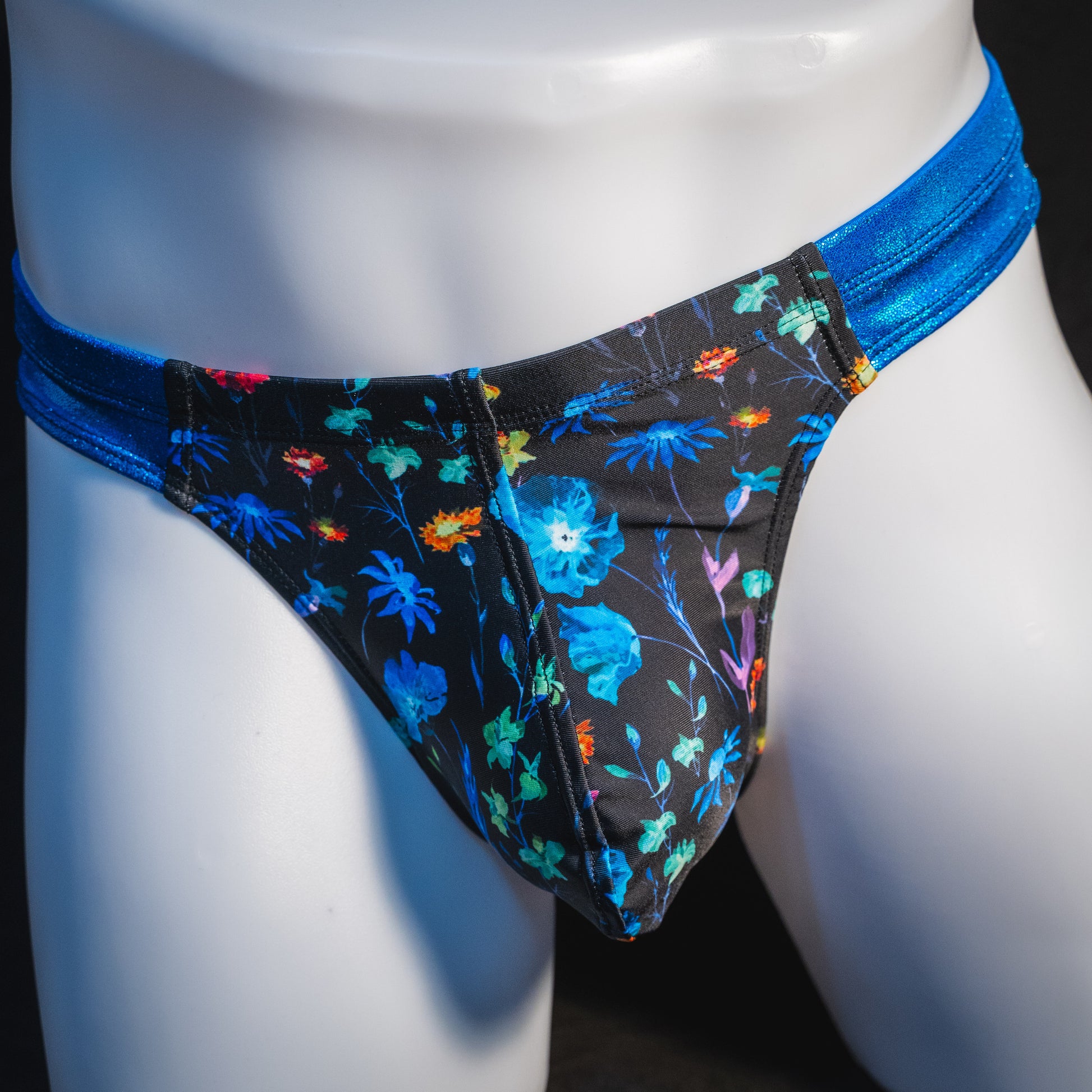 Men's floral thong underwear with metallic blue straps, robust cut, front view.