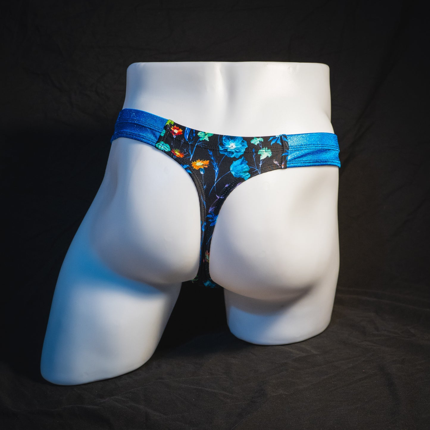 Men's floral thong underwear with metallic blue straps, robust cut, full Rear view.