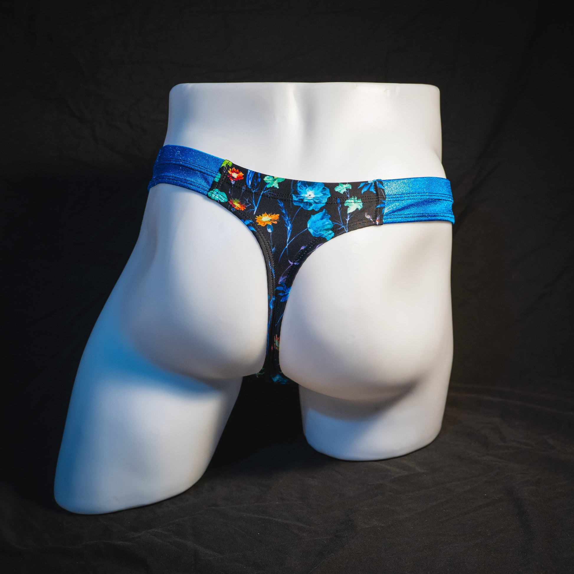 Men's floral thong underwear with metallic blue straps, robust cut, full Rear view.