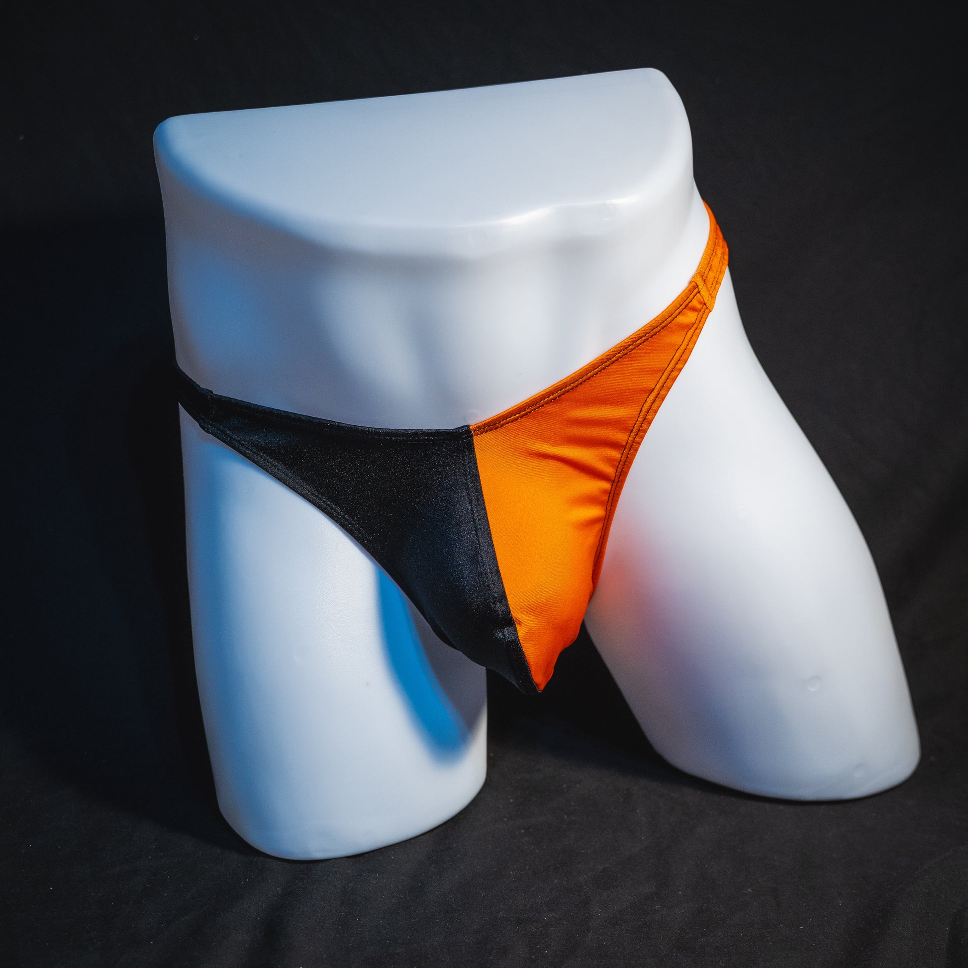 Men's orange and black asymmetrical Halloween thong, classic cut, full front view.