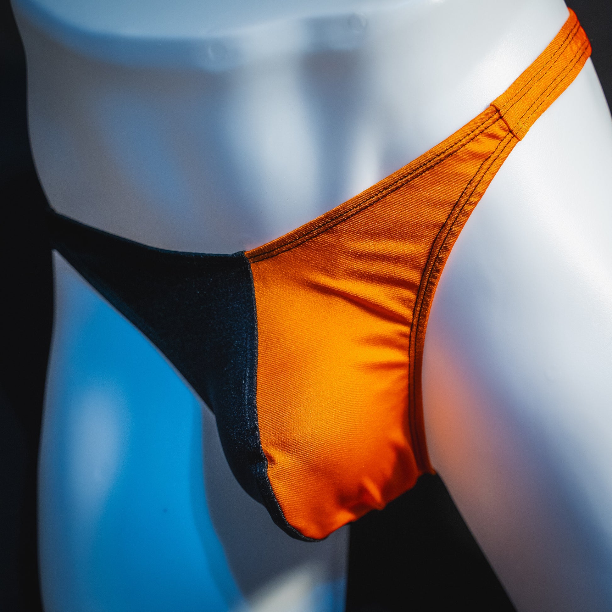 Men's orange and black asymmetrical Halloween thong, classic cut, angled front view.