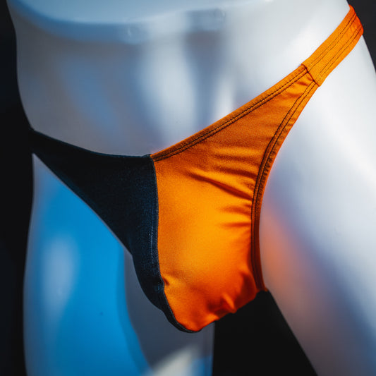 Men's orange and black asymmetrical Halloween thong, classic cut, angled front view.