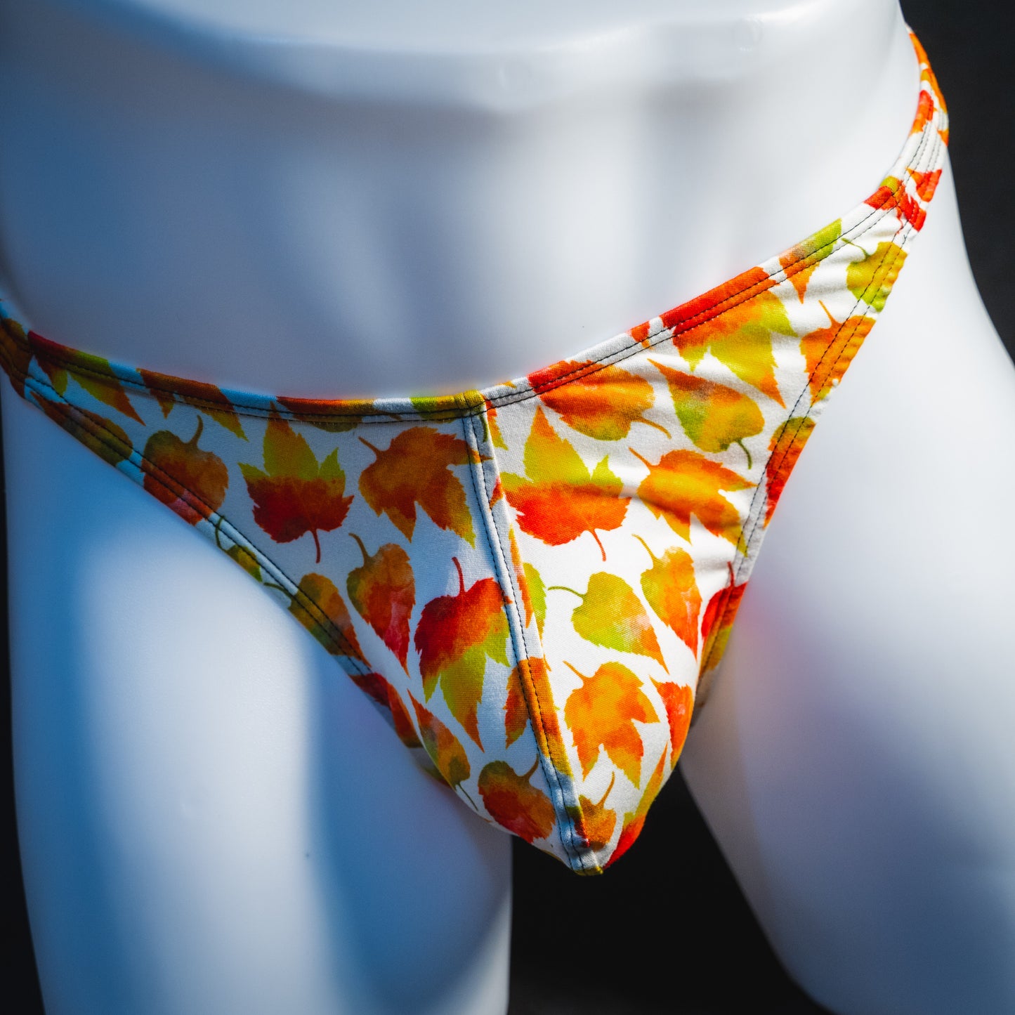 Men's orange autumn leaves thong underwear, classic cut, front view.