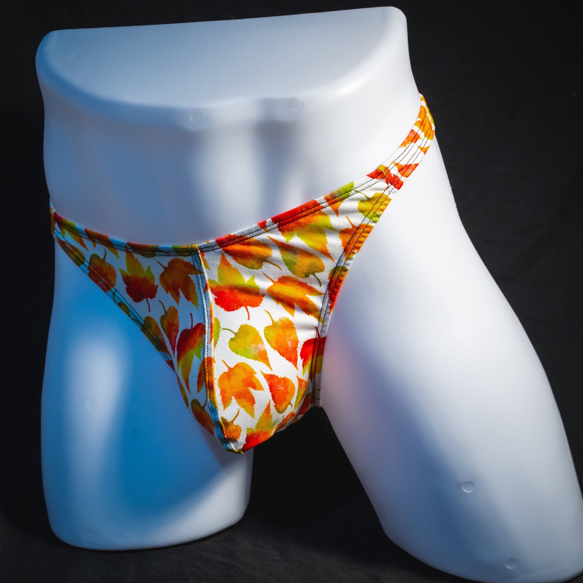 Men's orange autumn leaves thong underwear, classic cut, full angled front view.