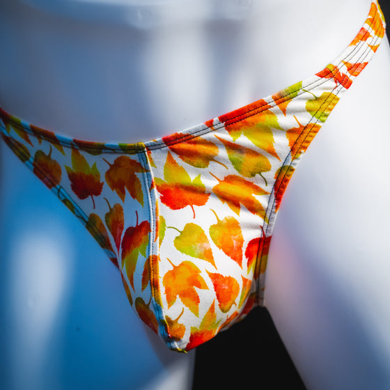 Men's orange autumn leaves thong underwear, classic cut, angled front view.