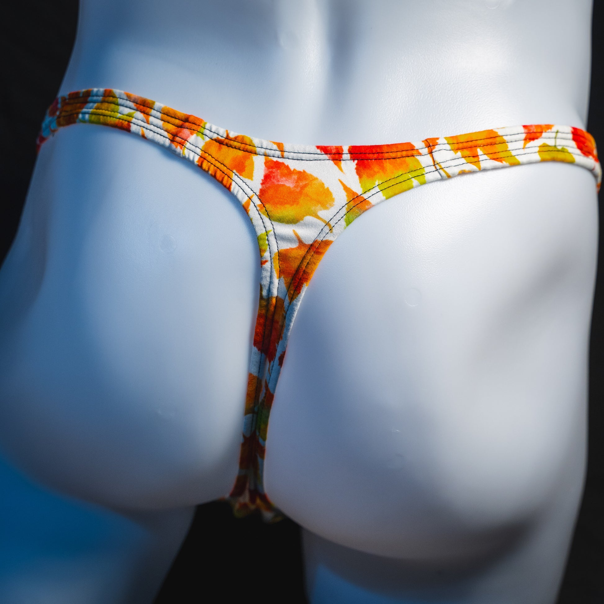 Men's orange autumn leaves thong underwear, classic cut, rear view.
