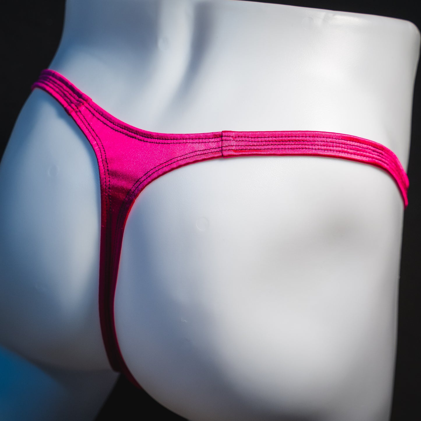 Men's rainbow splash with pink straps thong underwear, classic cut, angled rear view.