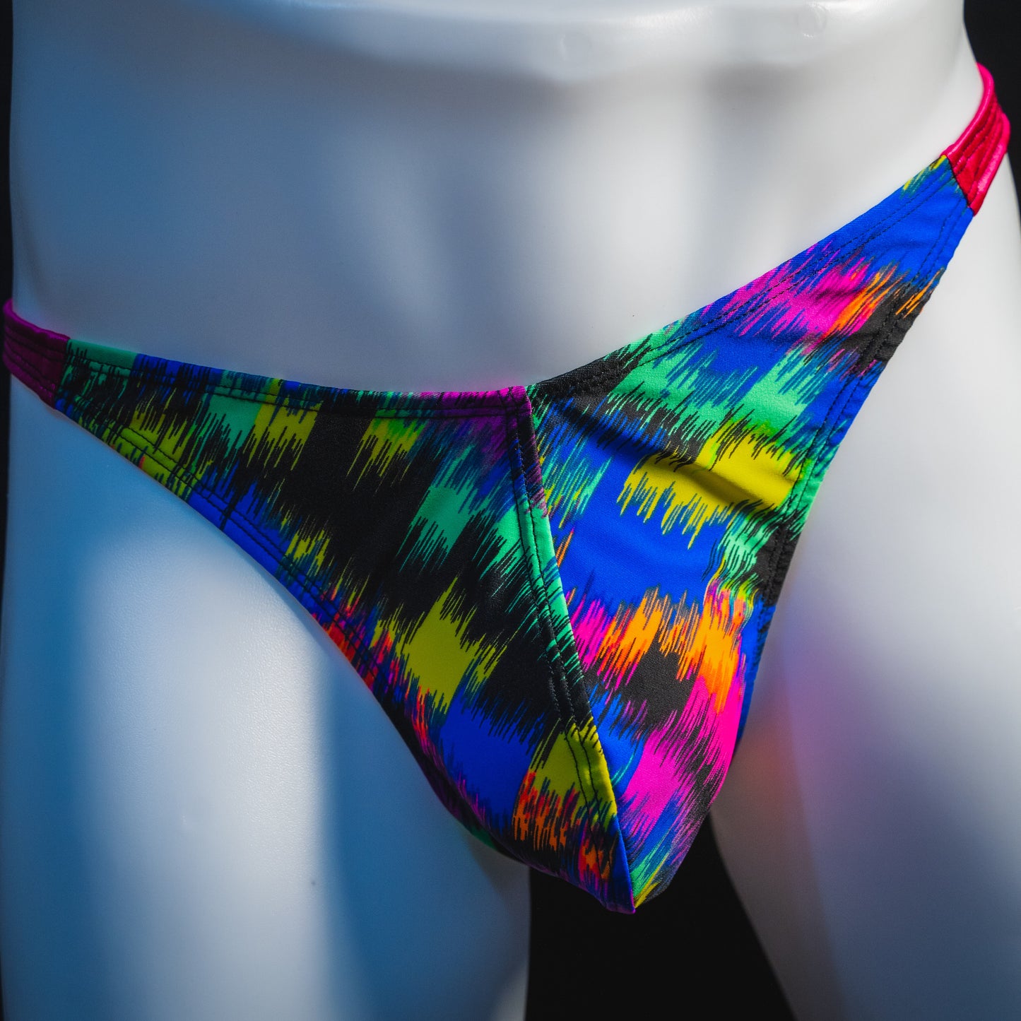 Men's rainbow splash with pink straps thong underwear, classic cut, front view.