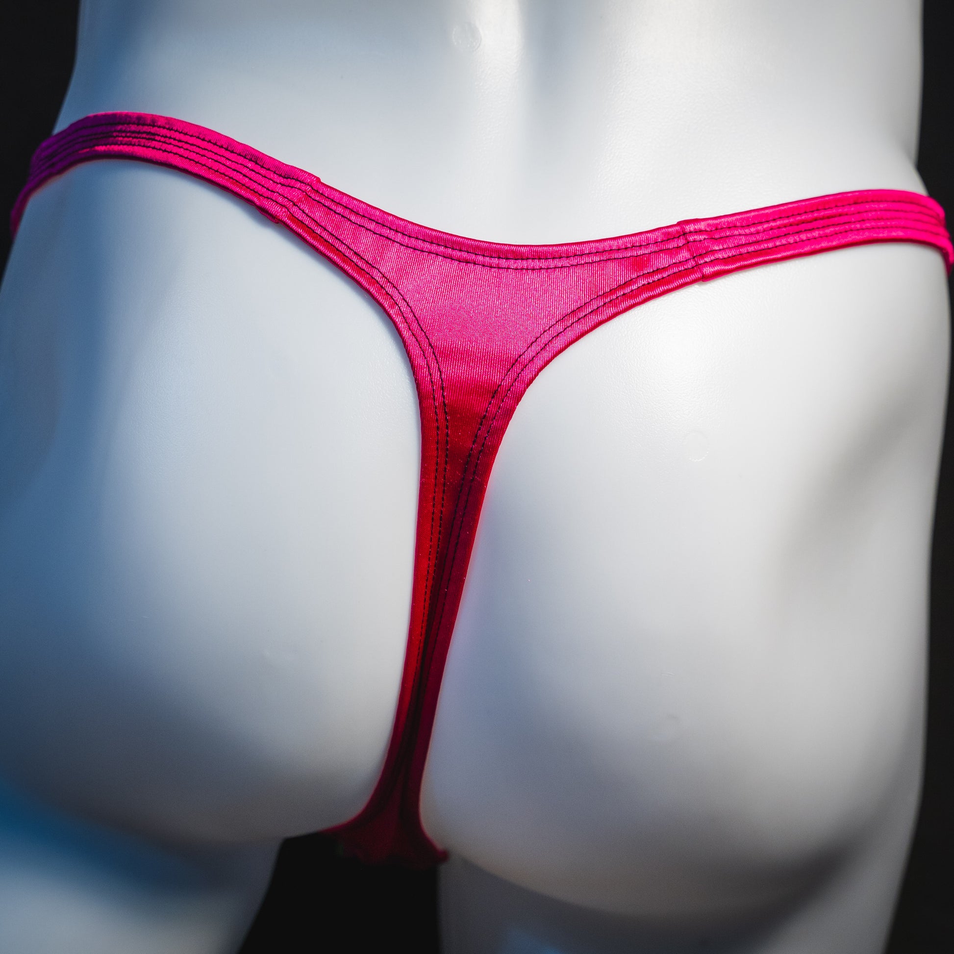 Men's rainbow splash with pink straps thong underwear, classic cut, rear view.