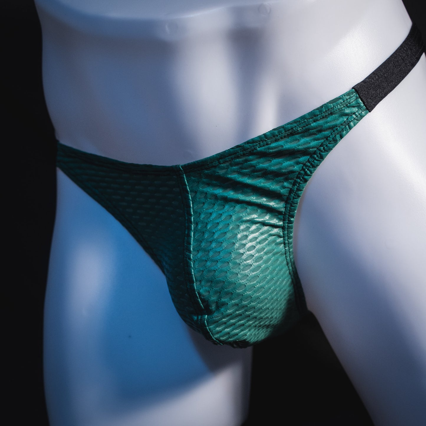 Men's green and black mesh thong underwear, classic cut, angled front view.