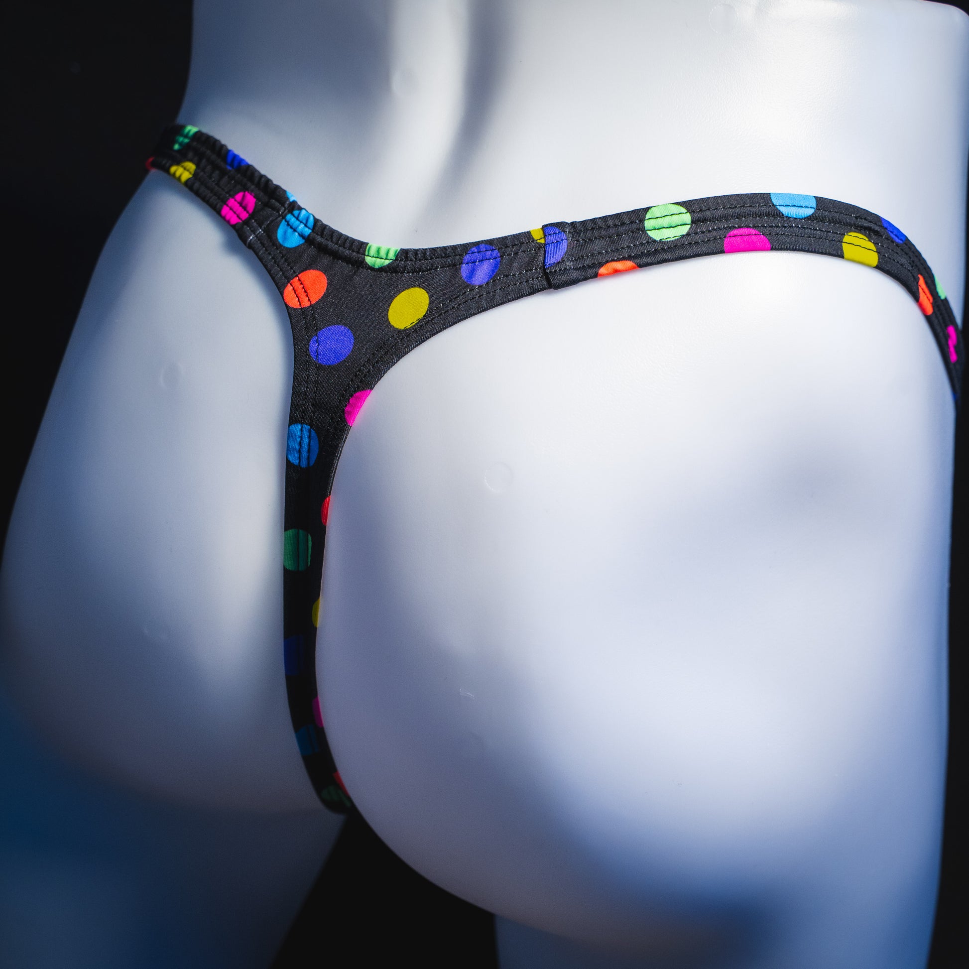 Men's multi colored polka dot thong underwear, classic cut, angled rear view.