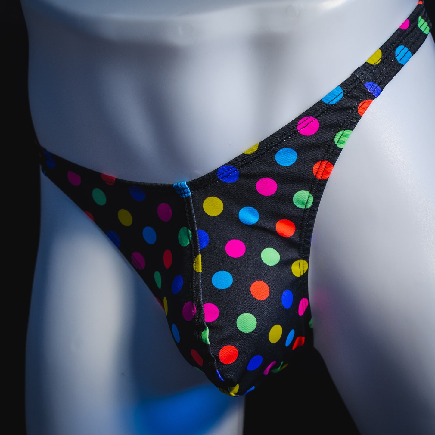 Men's multi colored polka dot thong underwear, classic cut, angled front view.