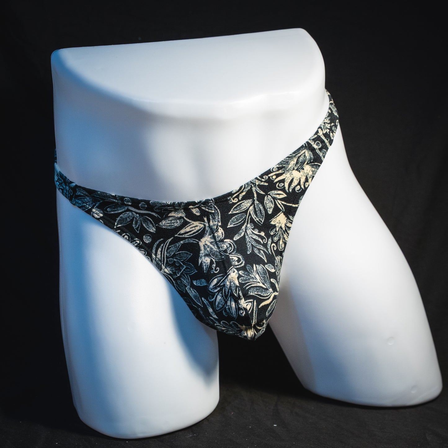 Men's black and white paisley thong underwear, classic cut, full front view.