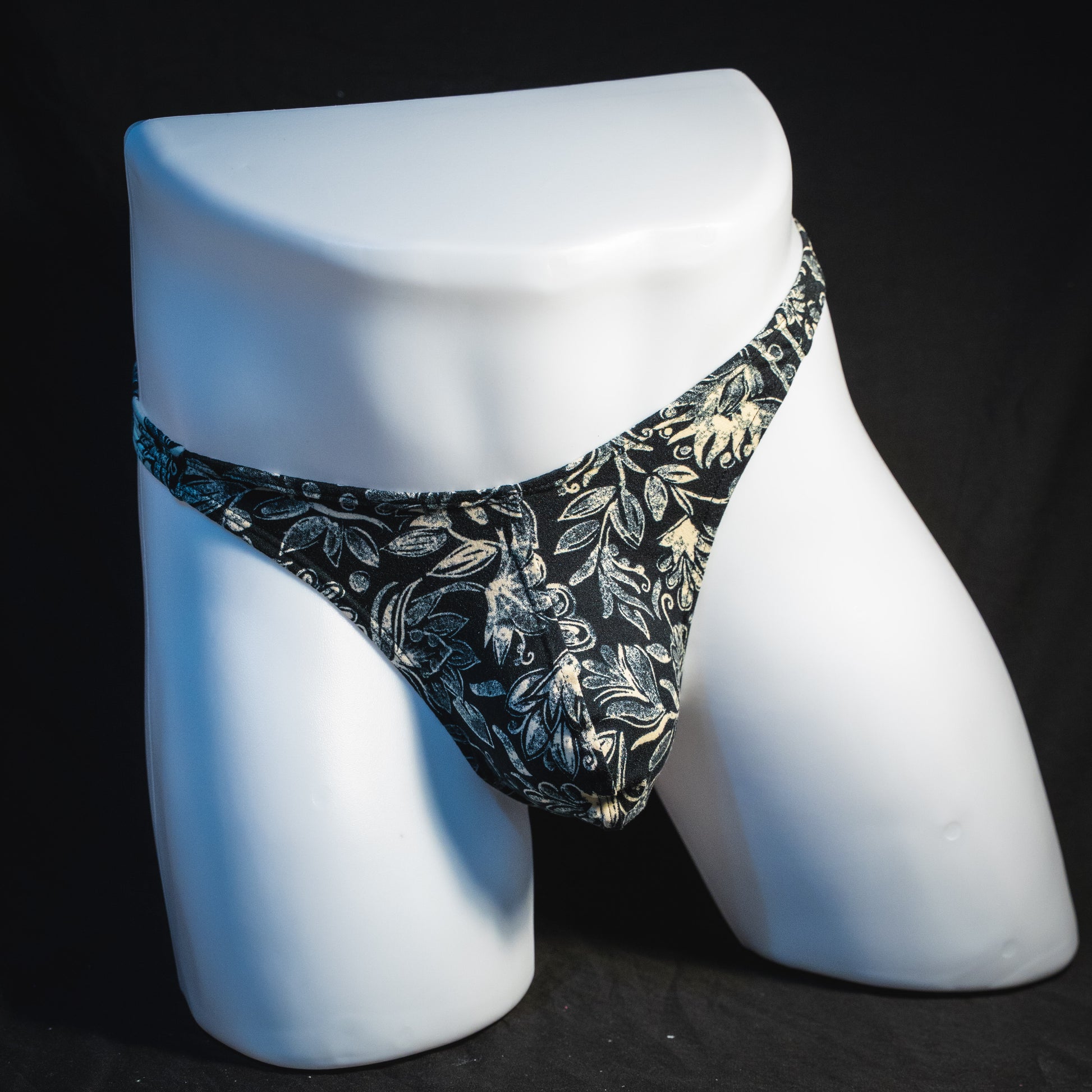Men's black and white paisley thong underwear, classic cut, full front view.