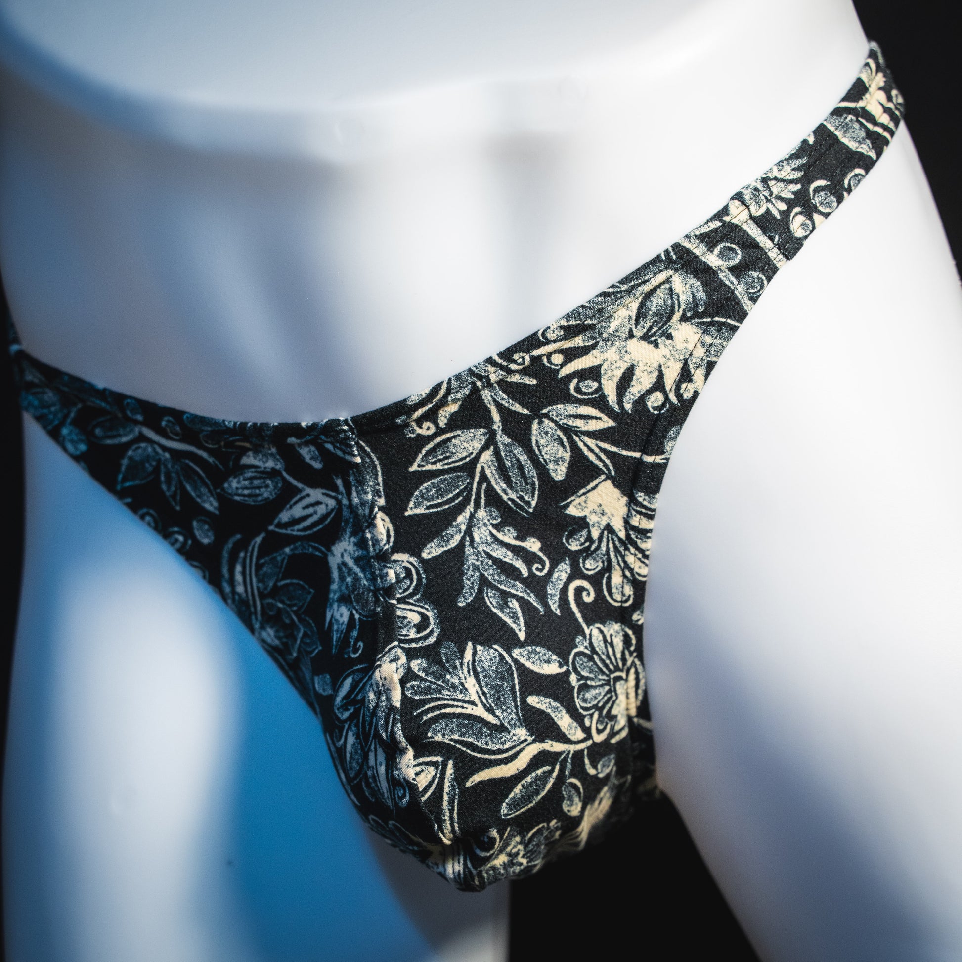 Men's black and white paisley thong underwear, classic cut, front angled view.