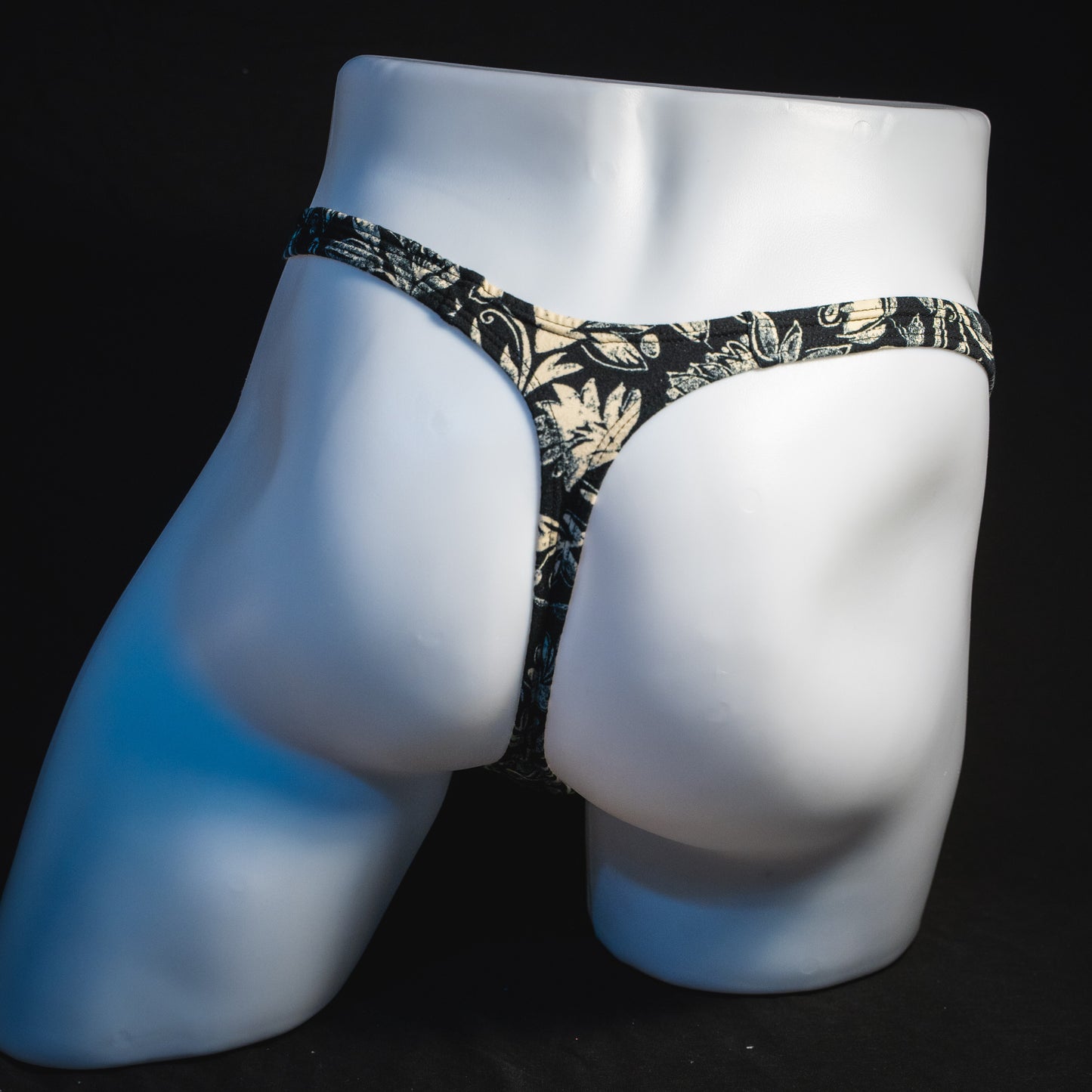 Men's black and white paisley thong underwear, classic cut, full rear view.