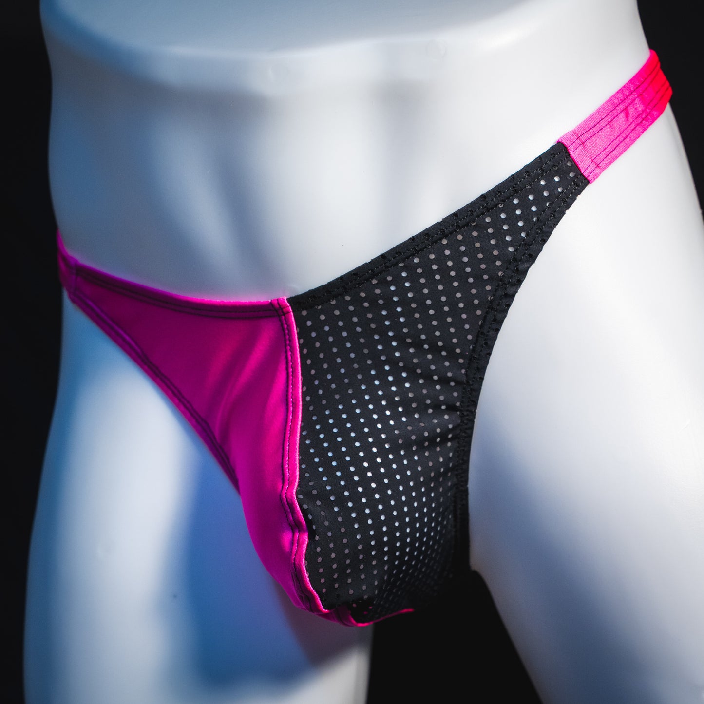 Men's bright pink and black mesh thong underwear, classic cut, angled front view.