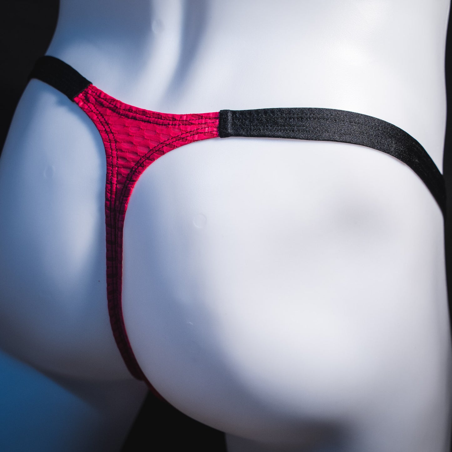 Men's pink athletic mesh thong underwear, classic cut, angled rear view.