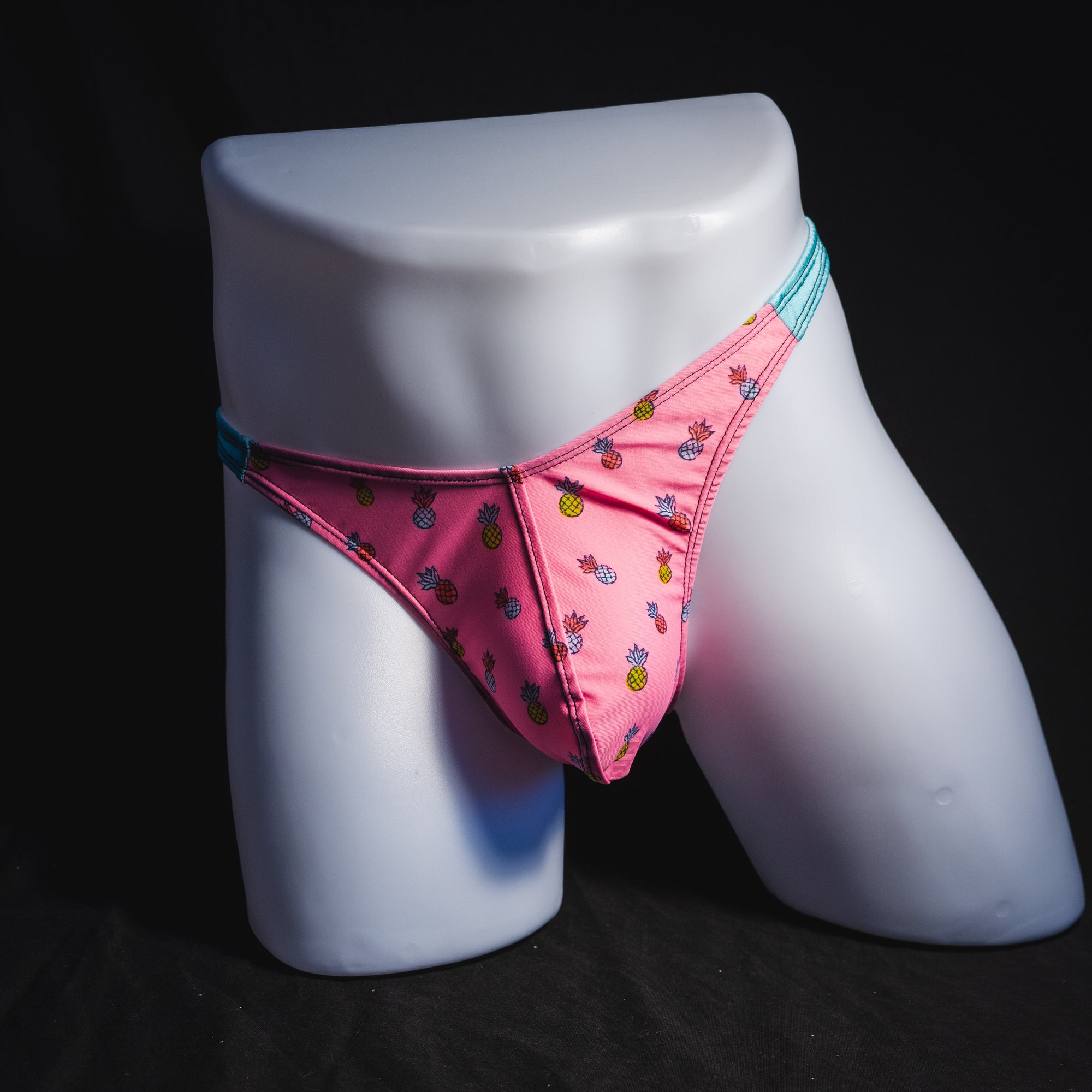 Men's bright pink and blue tropical thong underwear with pineapples, classic cut, full front view.