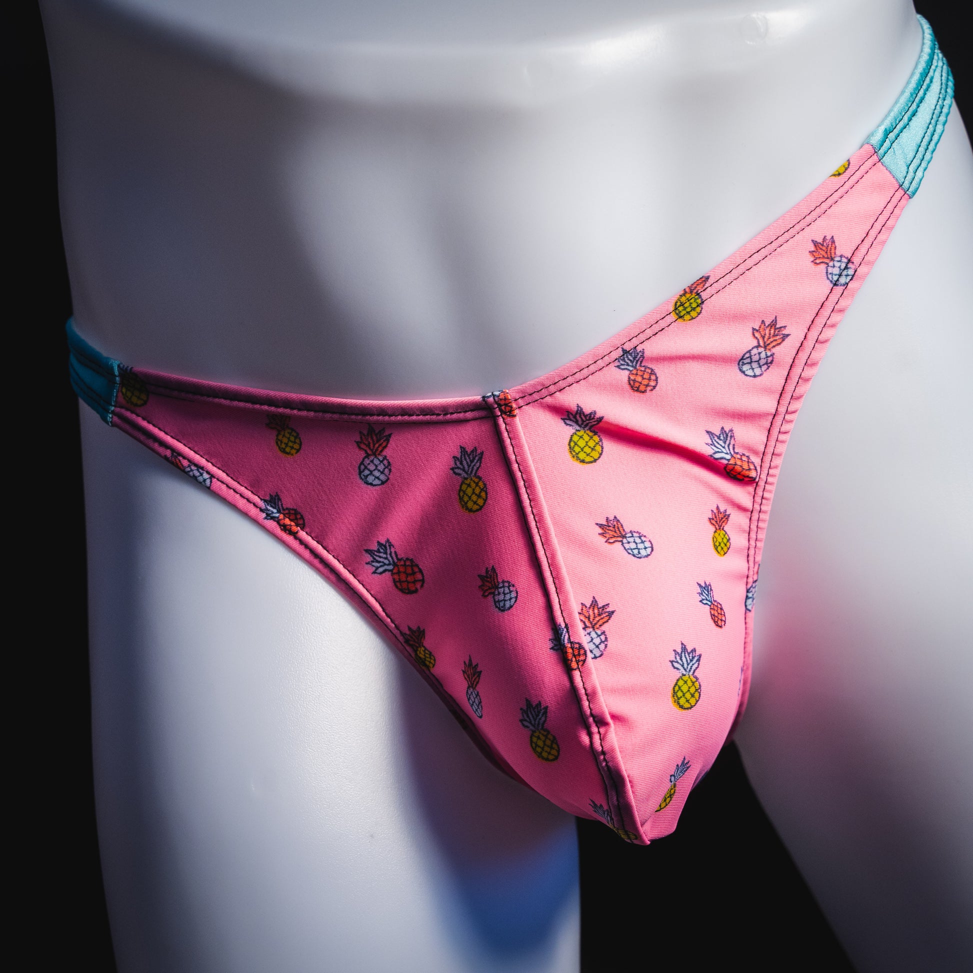 Men's bright pink and blue tropical thong underwear with pineapples, classic cut, front view.