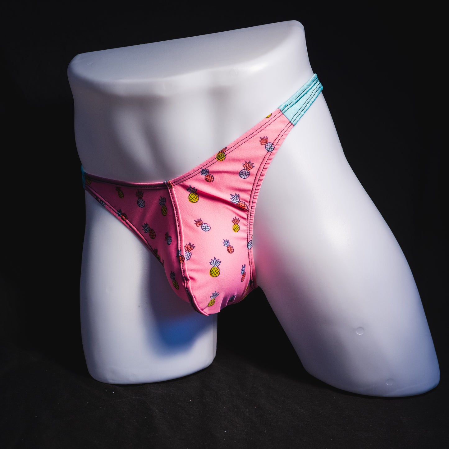Men's bright pink and blue tropical thong underwear with pineapples, classic cut, full angled front view.