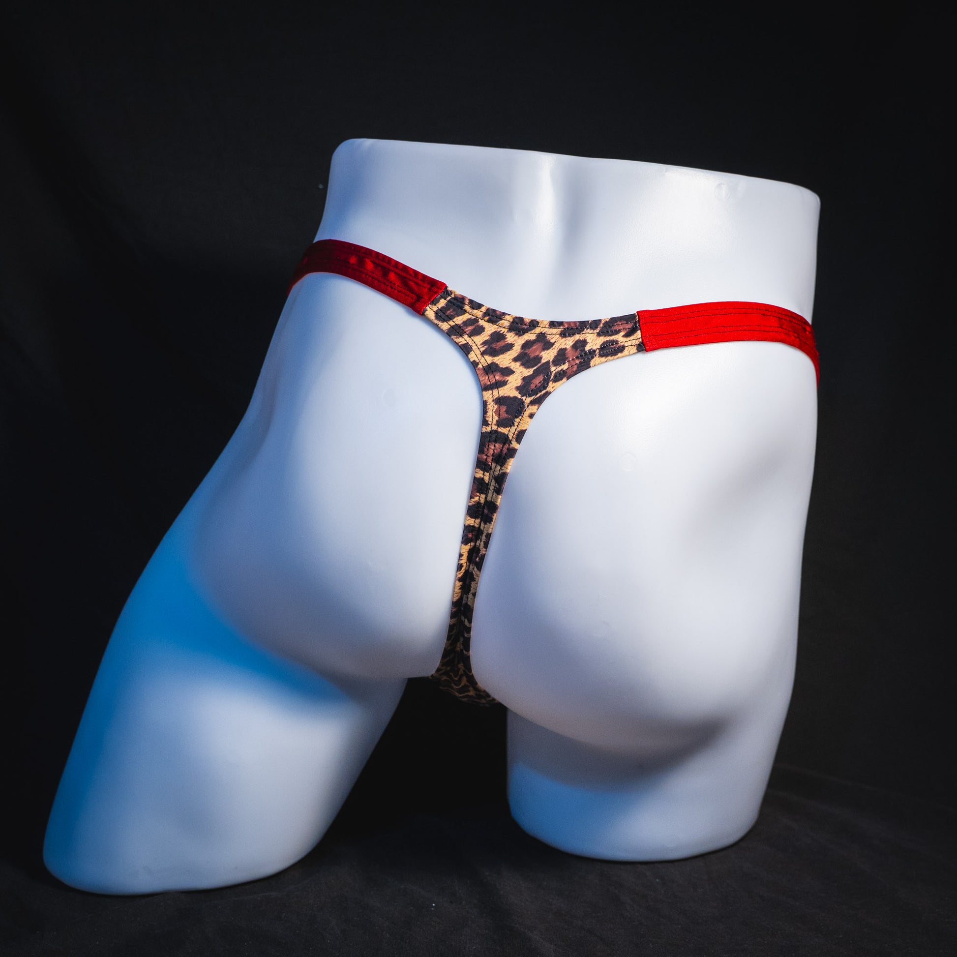 Men's cheetah print thong with red waistband, classic cut, full rear view.