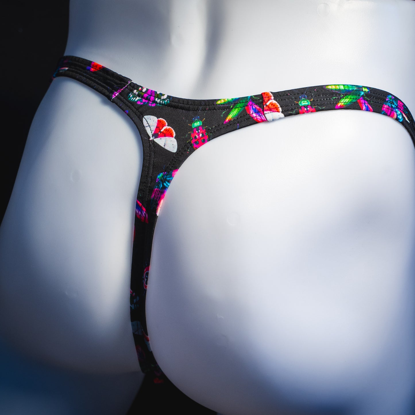 Men's black with pink insects thong underwear, Classic cut, rear angled view.