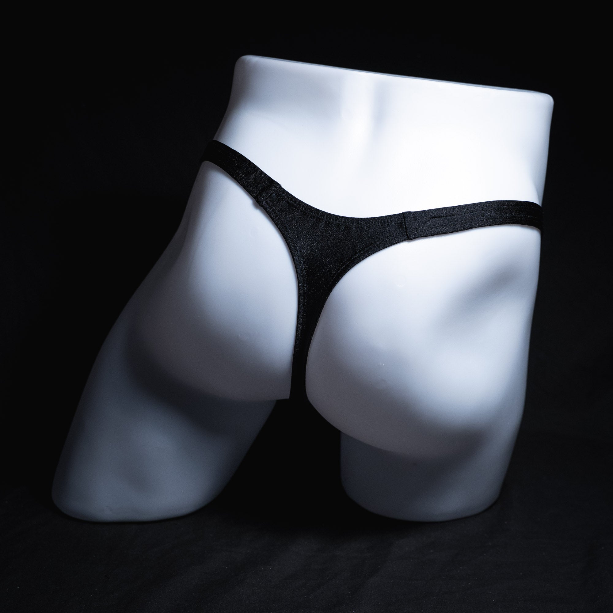 Men's solid black spandex thong underwear, classic cut, full rear view.