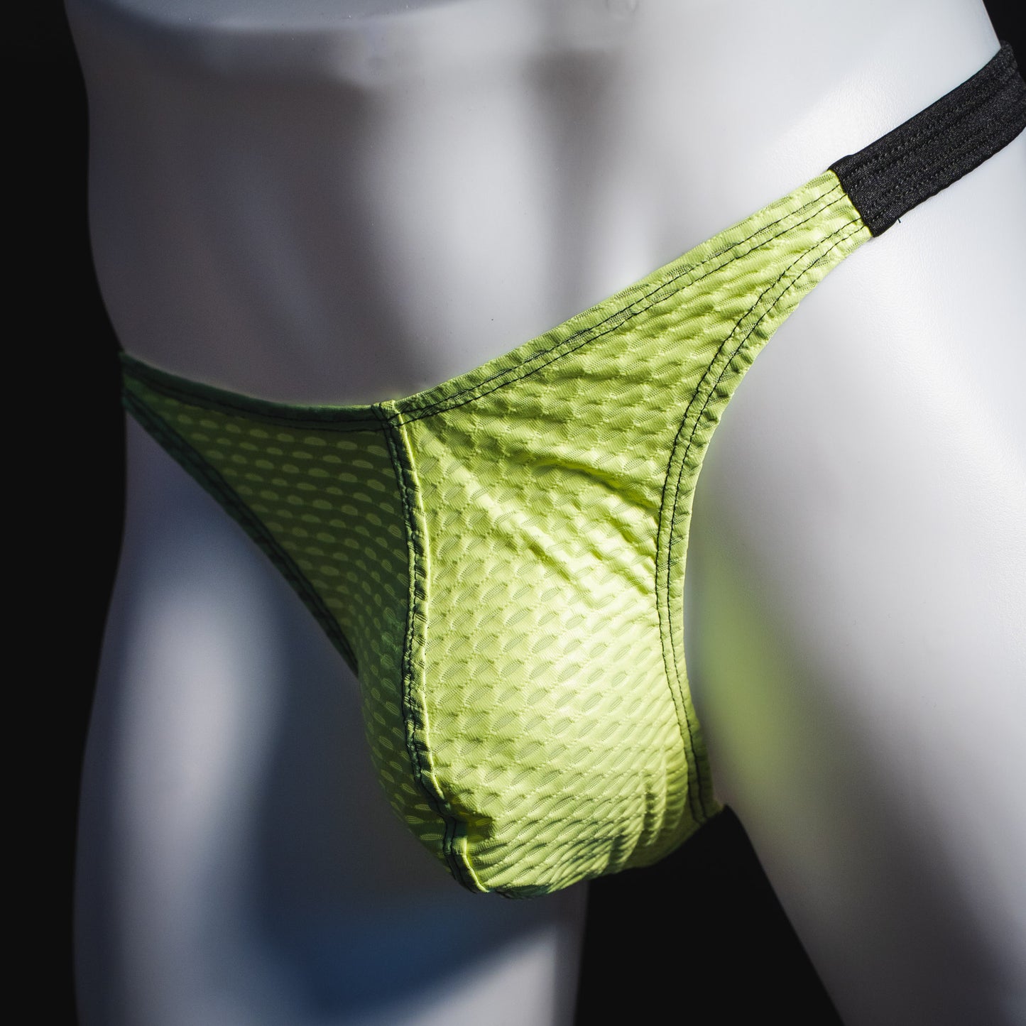 Men's lime green and black athletic mesh thong underwear, classic cut, angled front view.