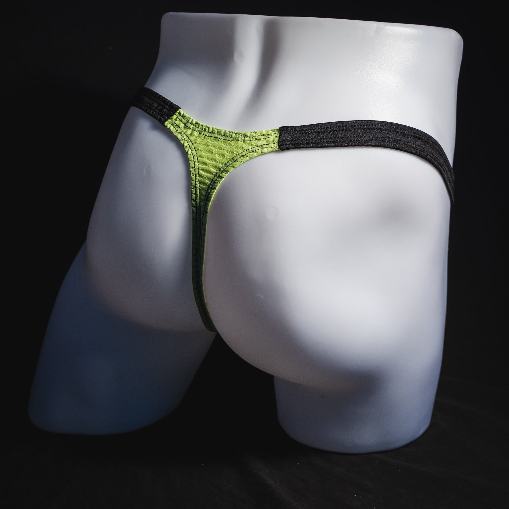 Men's lime green and black athletic mesh thong underwear, classic cut, full angled rear view.