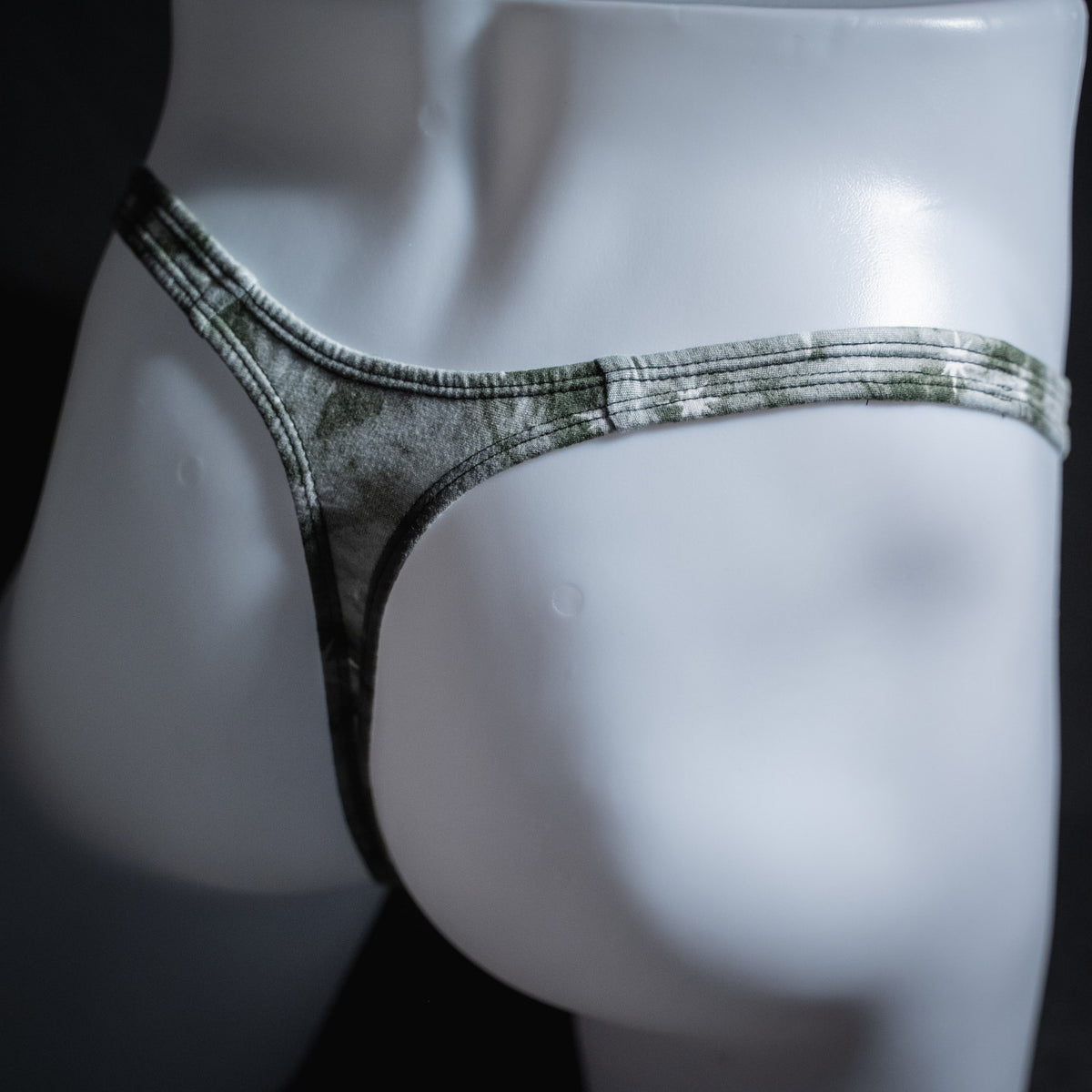 Men's grey tie dye with stars thong underwear, classic cut, angled rear view.