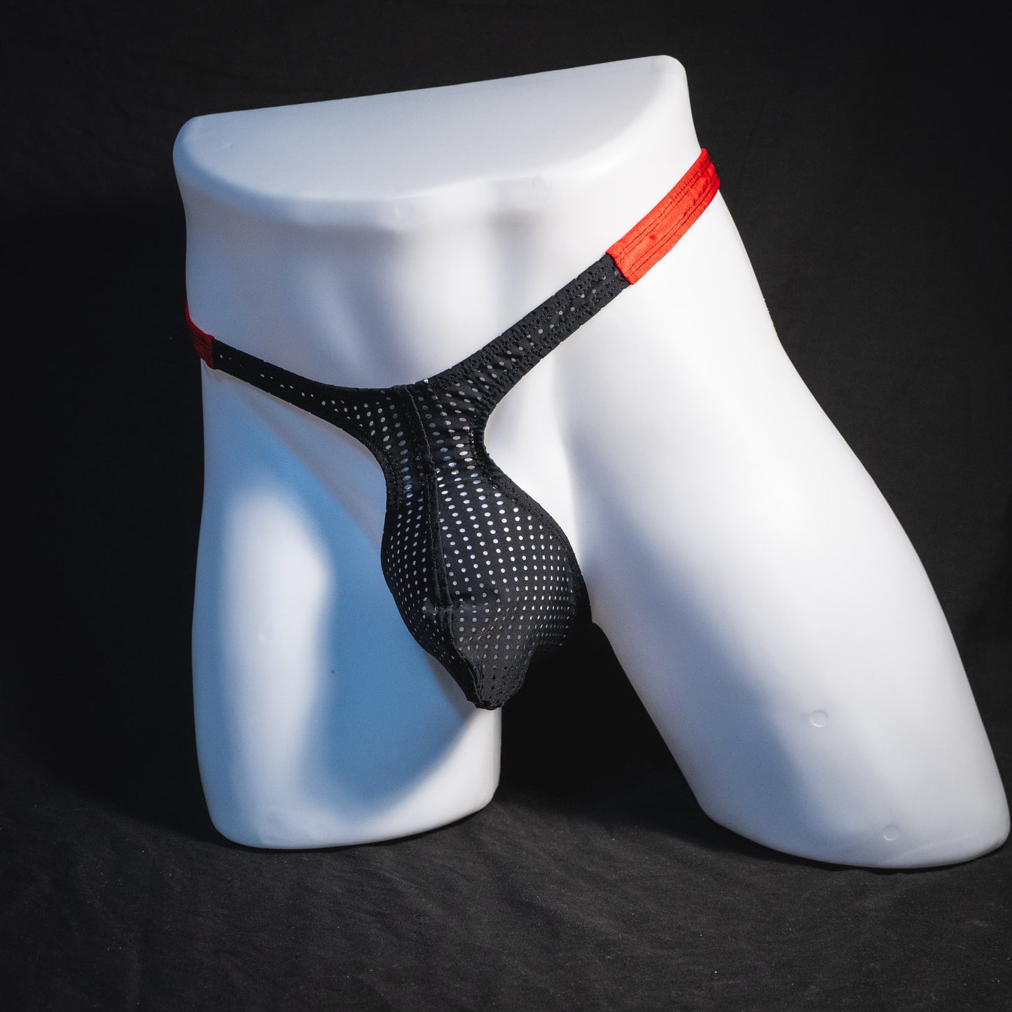 Men's black and red mesh thong underwear, classic cut, full angled front view.