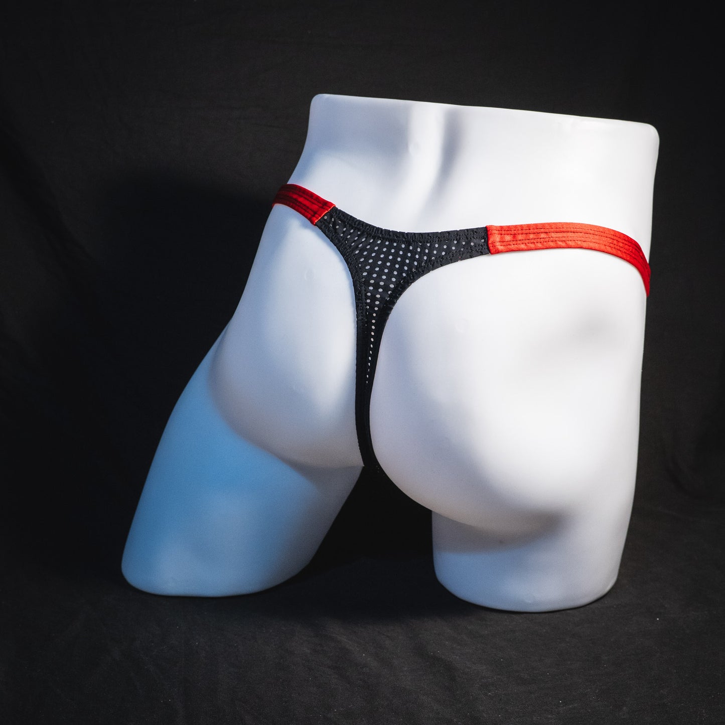 Men's black and red mesh thong underwear, classic cut, full angled rear view.