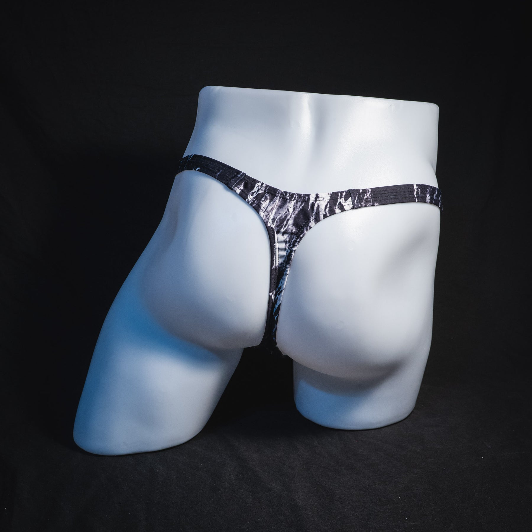 Men's black and white marble thong underwear, tower cut, full rear view.