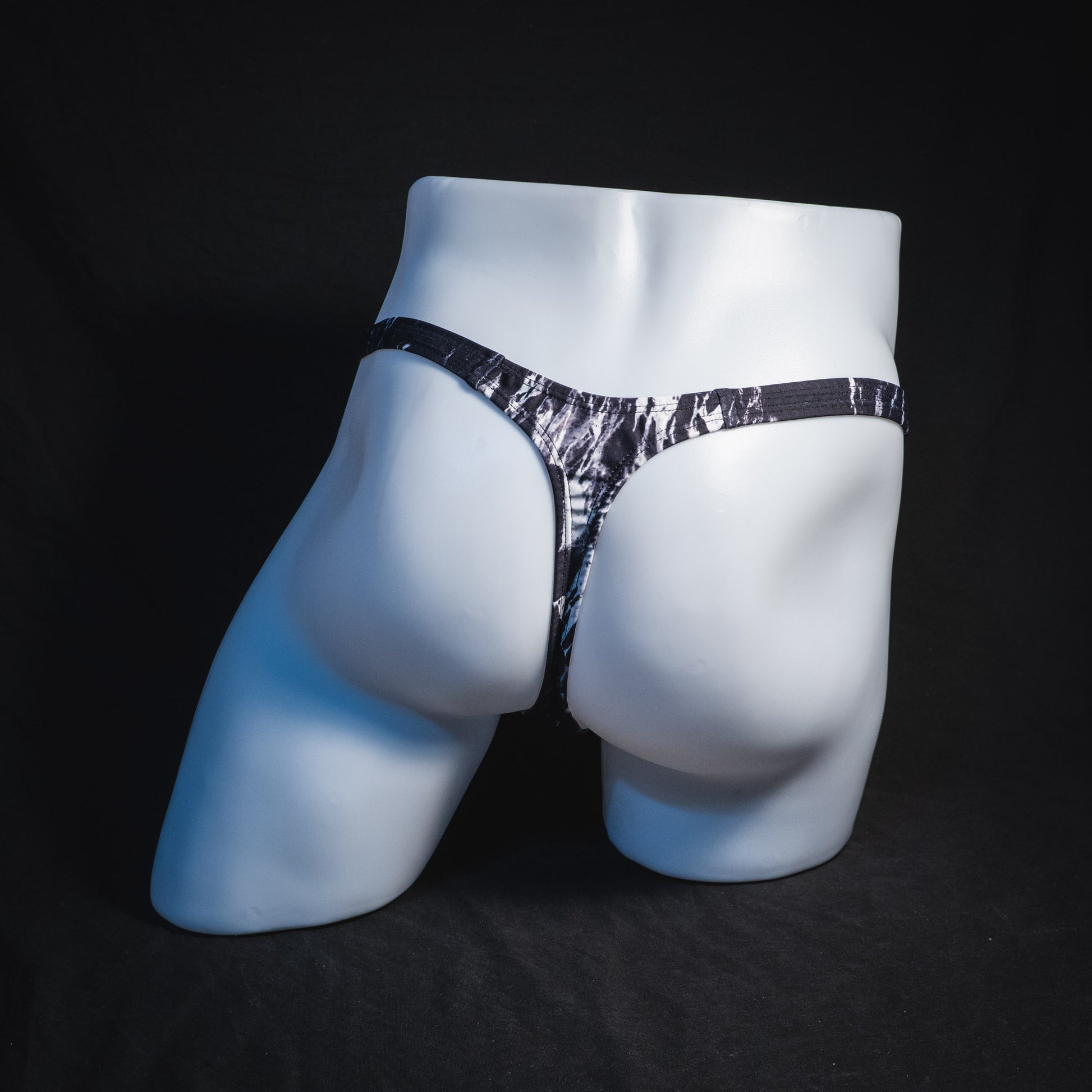 Men's black and white marble thong underwear, tower cut, full rear view.